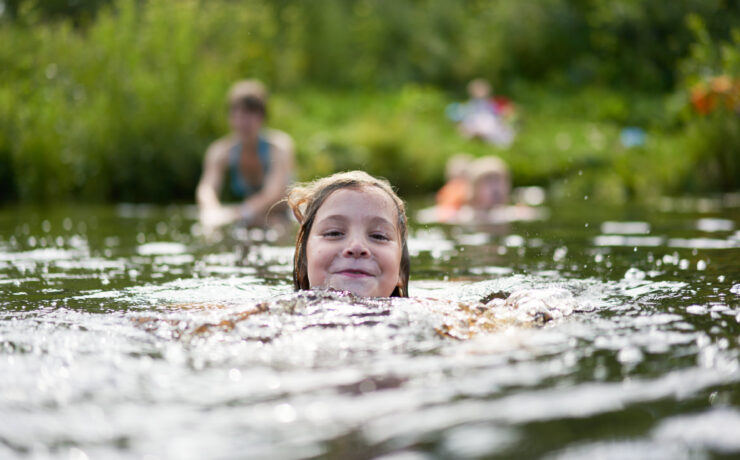 The Girl Swims Against The Background Of Bathing Other Family Members.