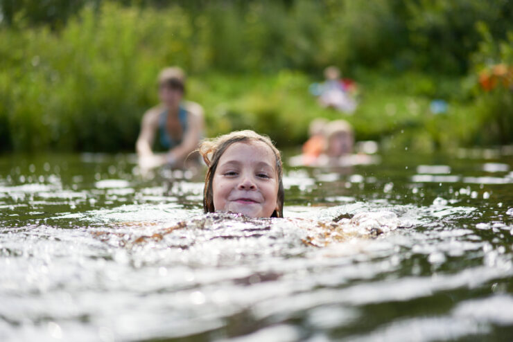The Girl Swims Against The Background Of Bathing Other Family Members.