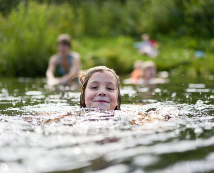 The Girl Swims Against The Background Of Bathing Other Family Members.