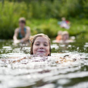 The Girl Swims Against The Background Of Bathing Other Family Members.
