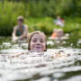 The Girl Swims Against The Background Of Bathing Other Family Members.
