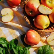 Fresh Red and Yellow Apples in Wicker Basket on Garden Picnic Table